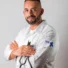 Man in a white coat holding a stethoscope with crossed arms