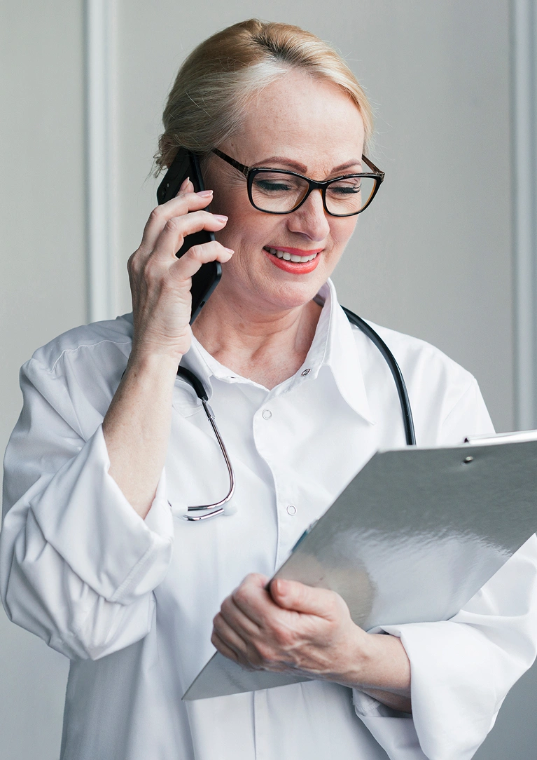 Woman in glasses and a white coat using a phone and tablet