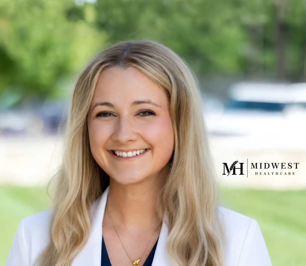 Portrait of a smiling adult in a white coat outdoors.